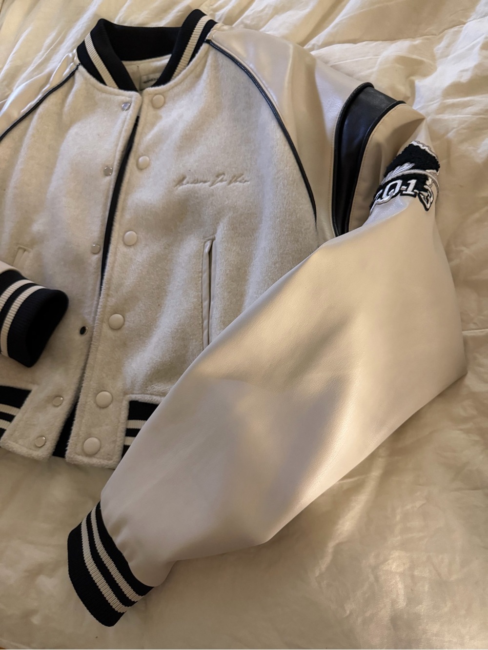Maniere De Voir Cropped Faux Leather Varsity Jacket in Cream and Black
